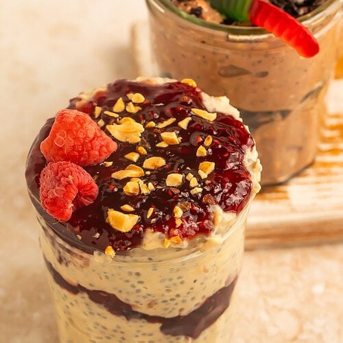 wo yogurt parfait jars, one layered with berry compote and raspberries and the other layered with chocolate cookie pieces and topped with a gummy worm