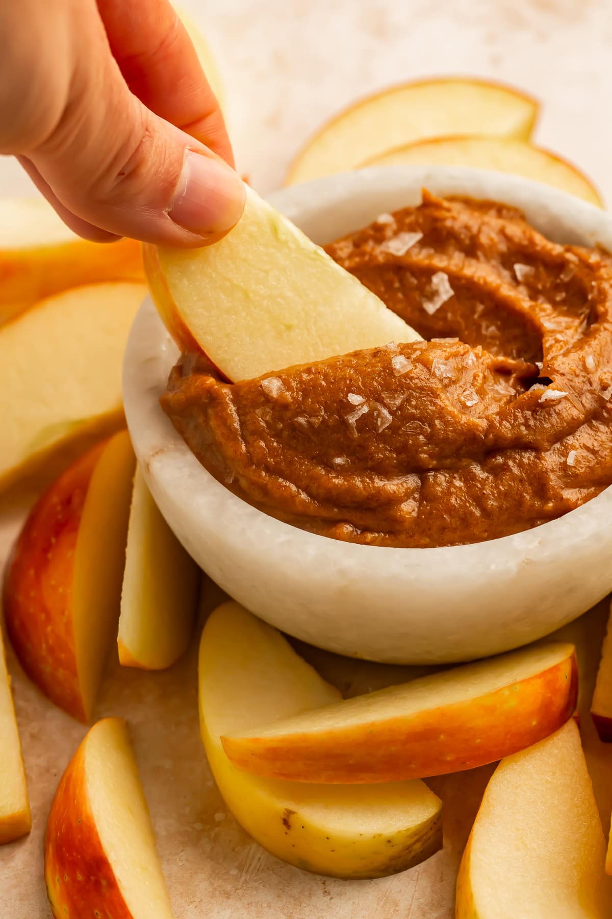 This paleo salted caramel is vegan, sugar free, and gluten free, but so delicious. It's quick and easy, and I promise you'll start putting it on everything. Made from only healthy ingredients, this vegan salted caramel is bound to become a staple in your home! Apple slice dipped into raw salted caramel dip topped with flaky sea salt