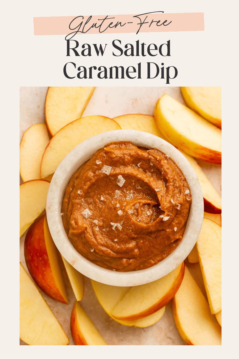 Overhead view of a white marble bowl filled with raw salted caramel dip topped with flaky sea salt surrounded by apple slices