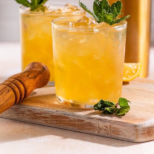 Two bourbon smashes pictured side on, garnished with fresh mint.