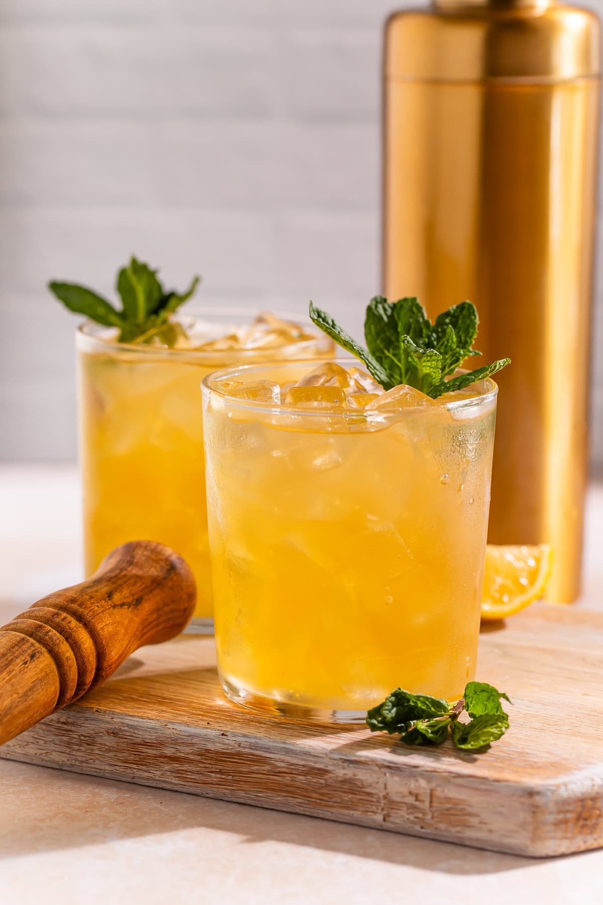 Two bourbon smashes pictured side on, garnished with fresh mint.