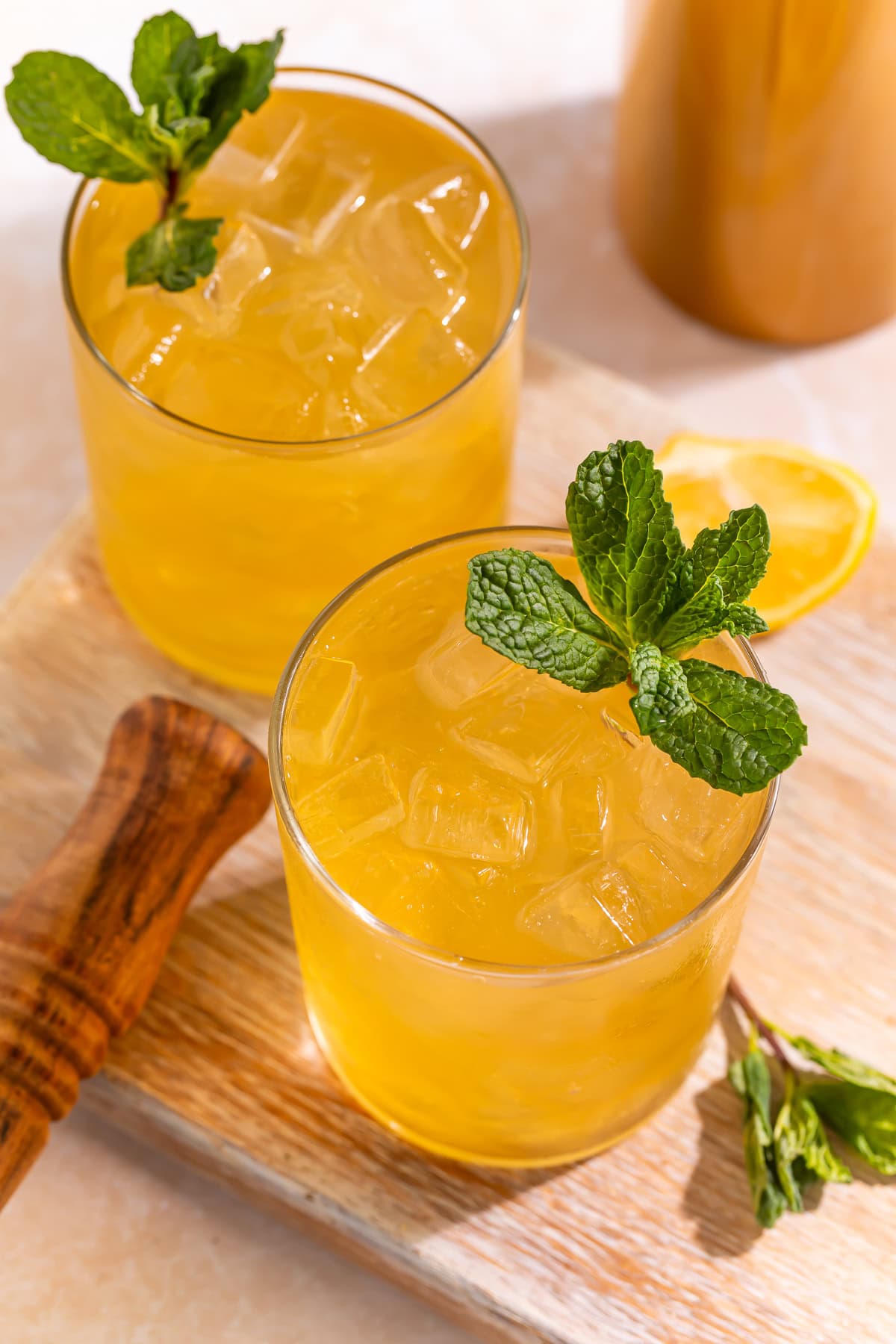 Overhead view of two Bourbon smash cocktails on a cutting board, garnished with sprigs of mint.