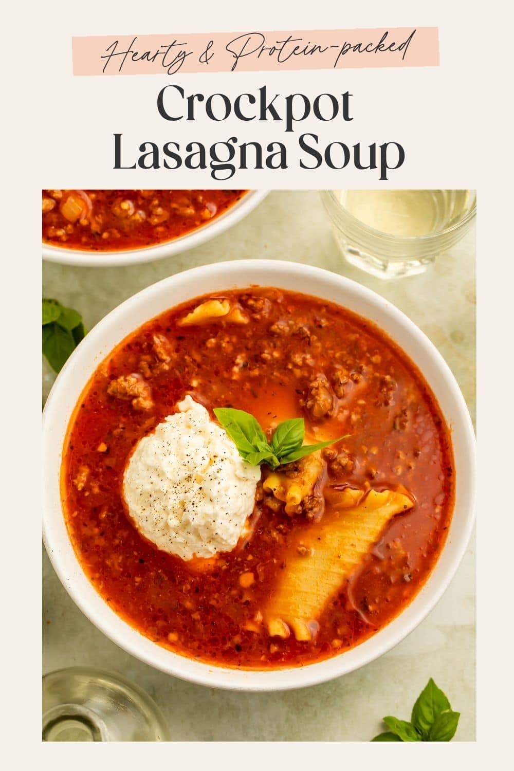Close up of a blow of lasagna soup with visible noodles, a scoop of ricotta and a fresh basil leaf. There is a frame on the image with Pinterest-optimised text.