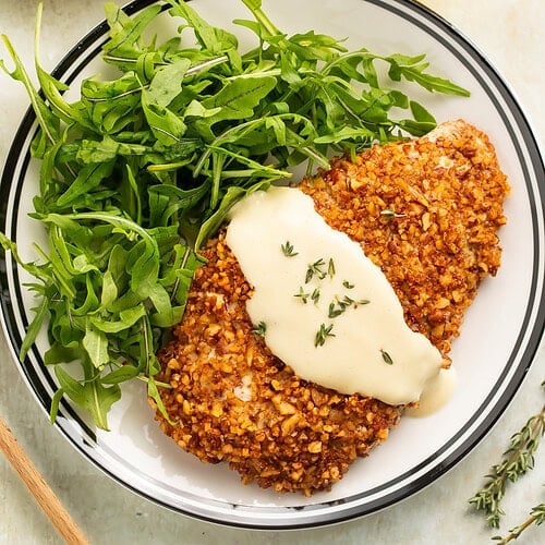 Close up of a plate of pecan crusted chicken cutlets with honey mustard sauce.