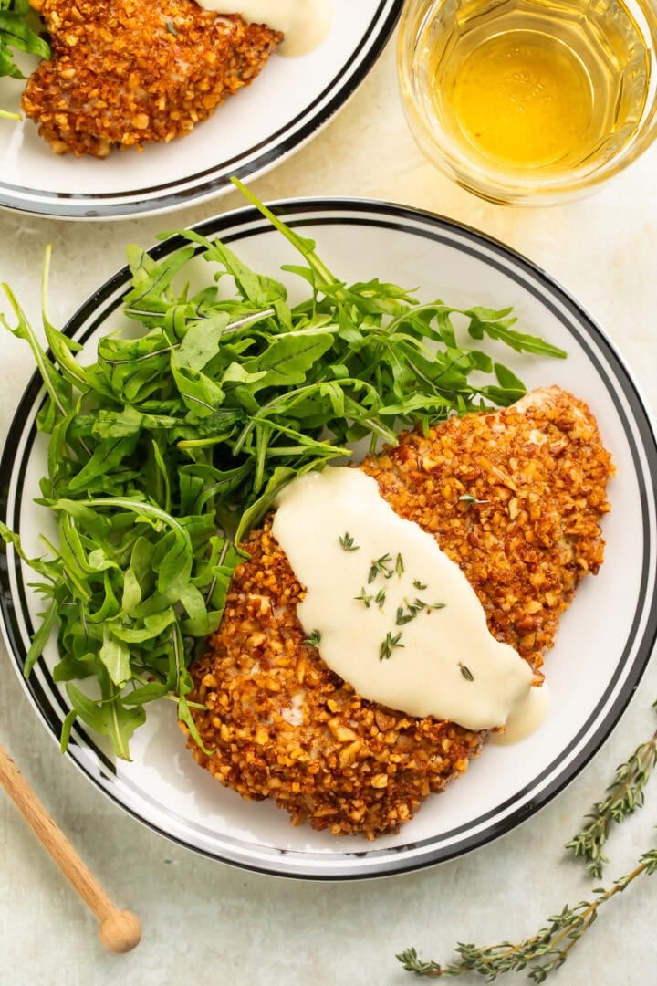Close up of a plate of pecan crusted chicken cutlets with honey mustard sauce.