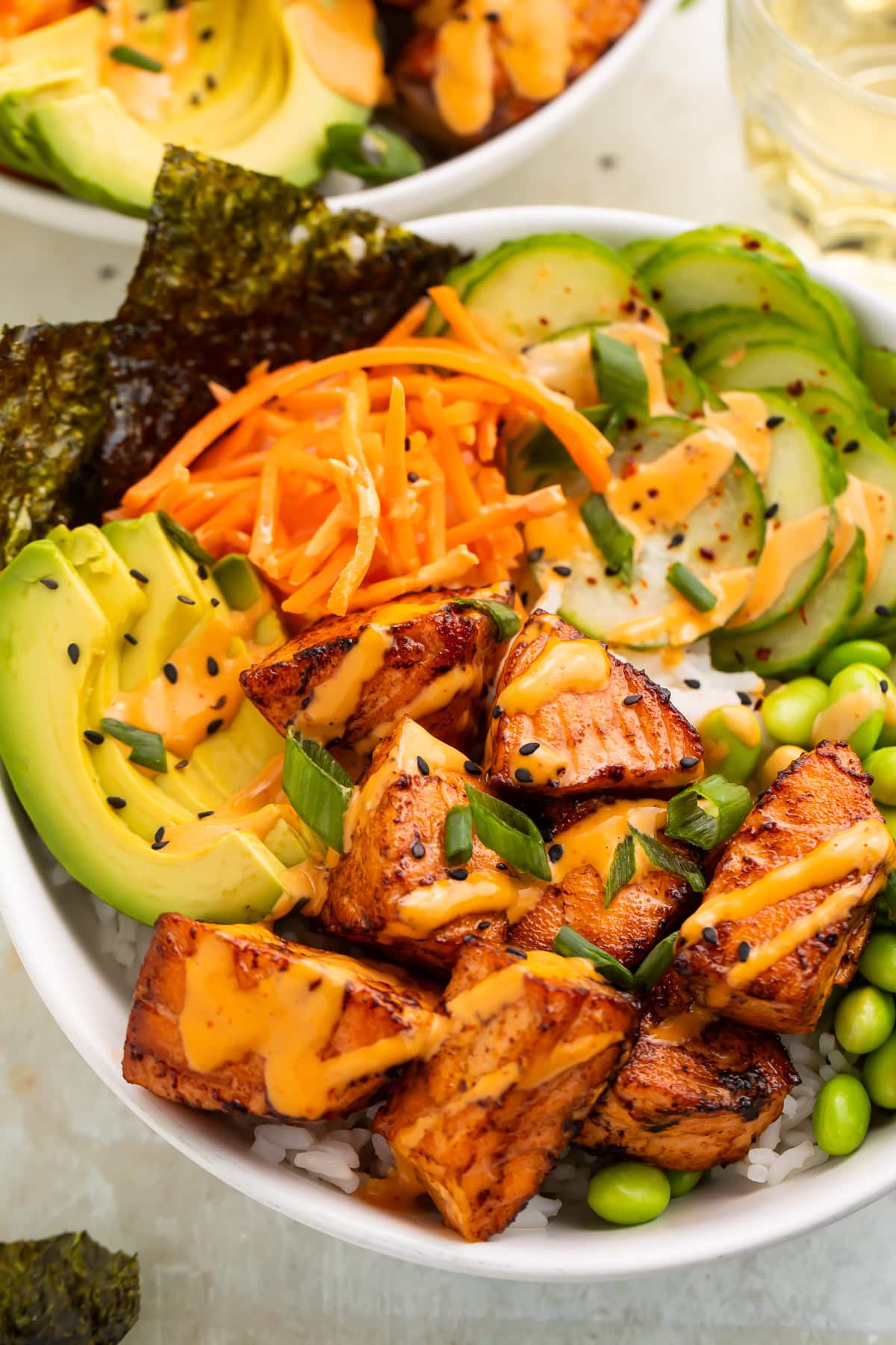 Close up of caramalised salmon bites in a rice bowl with Asian-inspired ingredients.