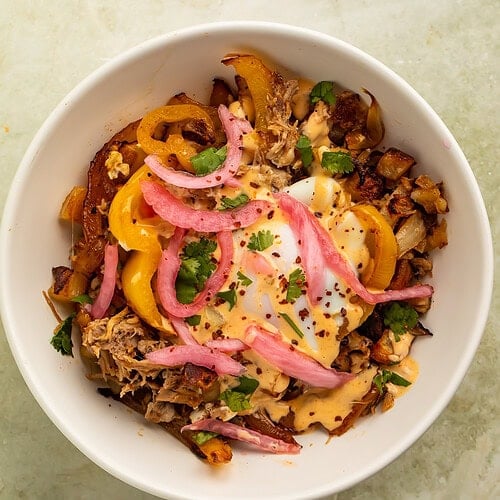 Smoky pulled pork breakfast hash topped with eggs, pickled onions, peppers, and chipotle crema.