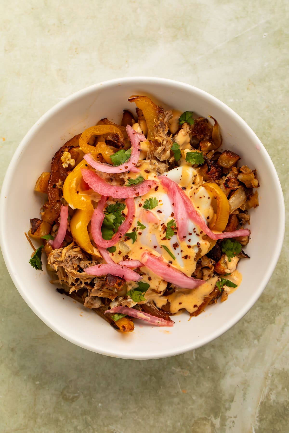 Smoky pulled pork breakfast hash topped with eggs, pickled onions, peppers, and chipotle crema.