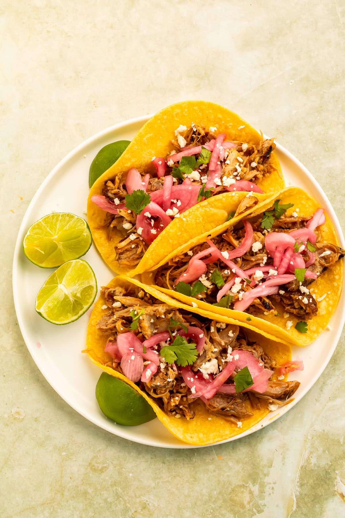 Chipotle pulled pork street tacos topped with pickled red onions, cotija cheese, cilantro, and fresh lime.