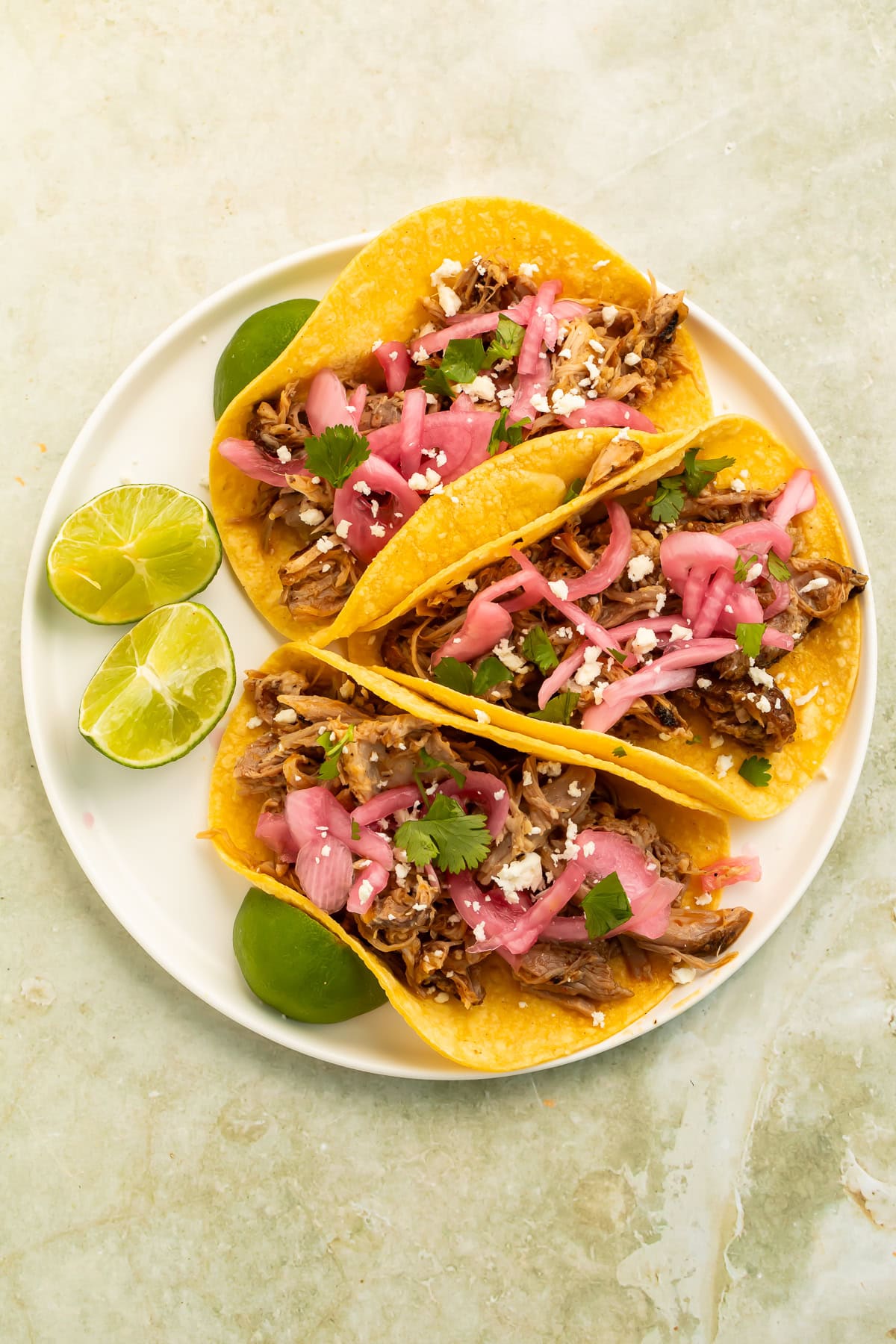 Pulled pork tacos with pickled onions, cilantro, cotija cheese, and fresh lime.