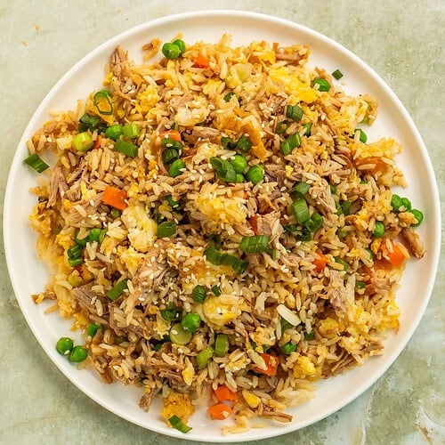 Chipotle pork fried rice with eggs, peas, carrots, scallions, and sesame seeds.