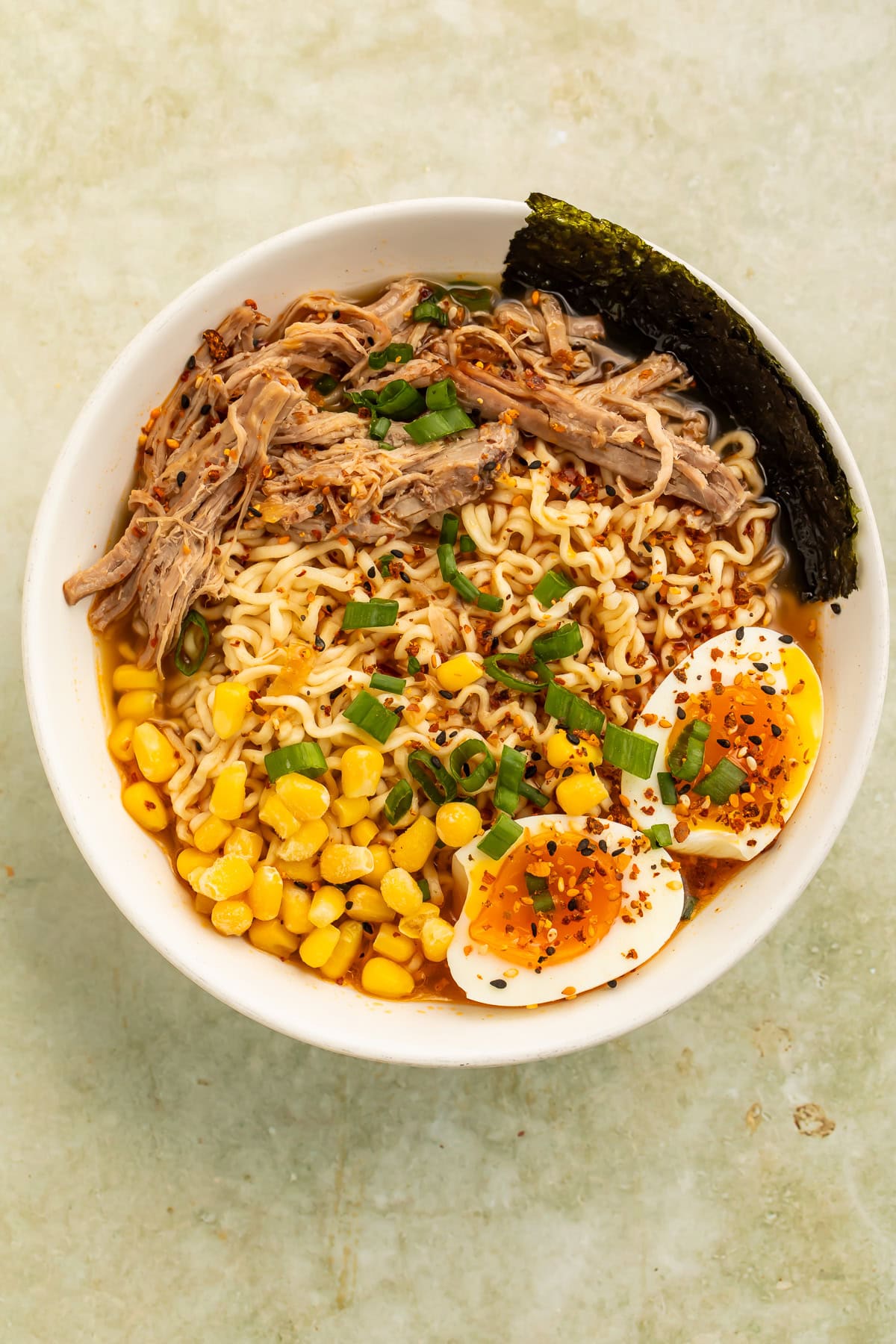 Chipotle pork ramen bowl with soft-boiled egg, corn, scallions, and savory broth