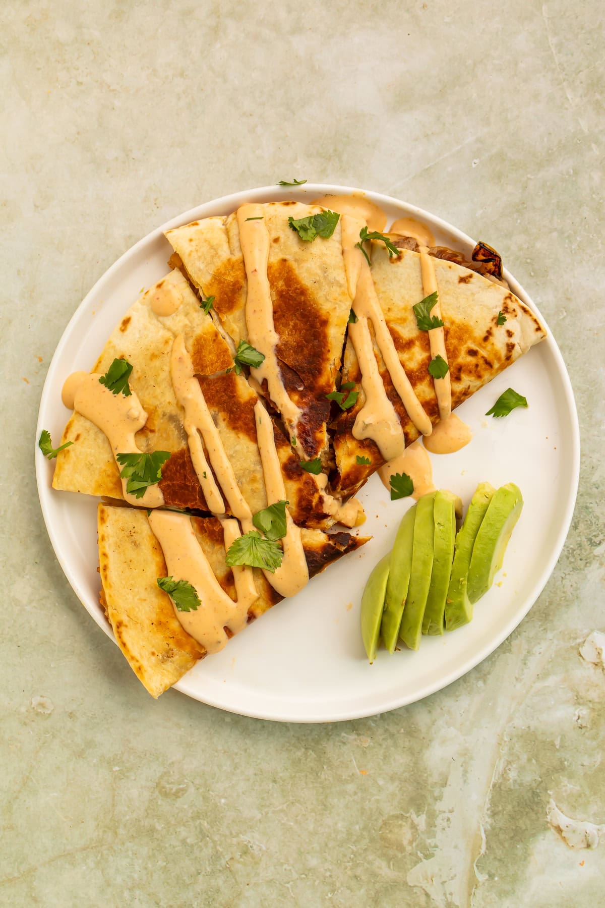 Loaded pulled pork quesadillas with chipotle crema, avocado slices, and fresh cilantro.