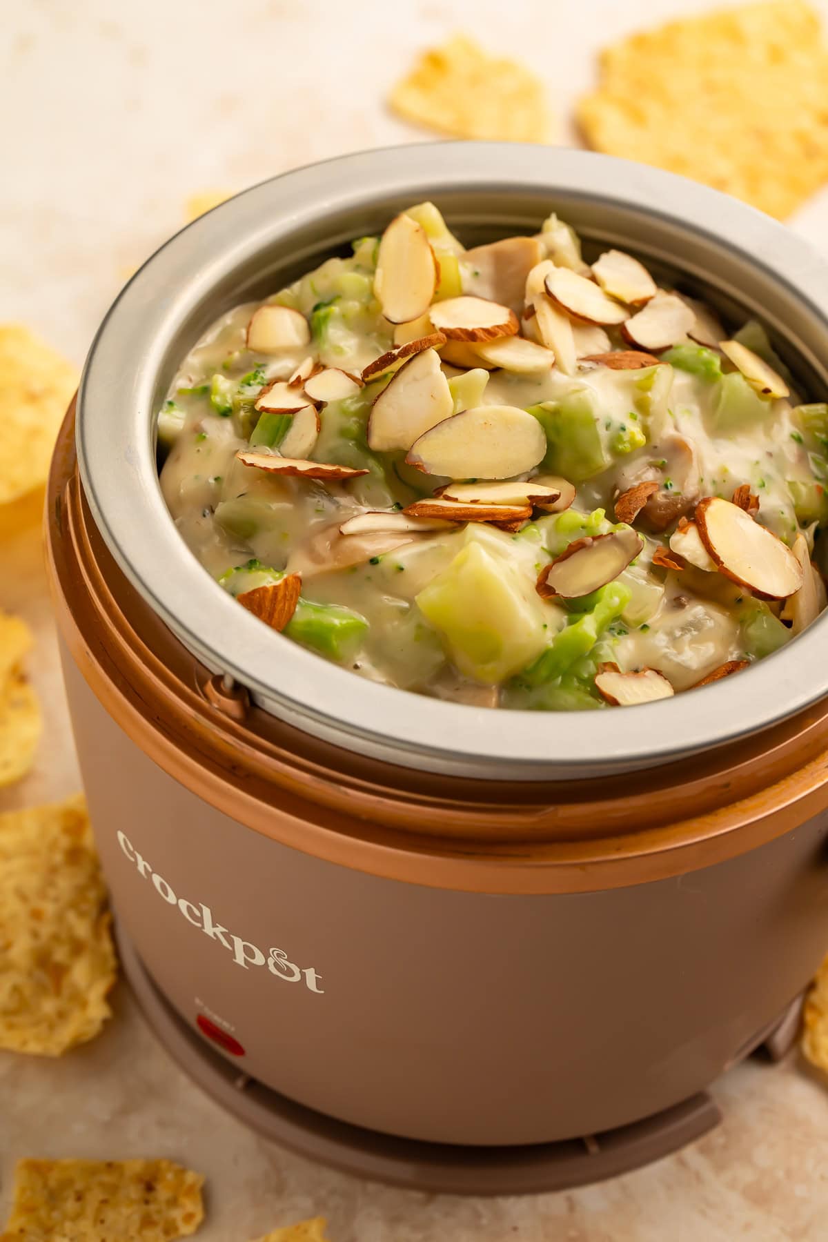 Mini crockpot of broccoli dip topped with sliced almonds.