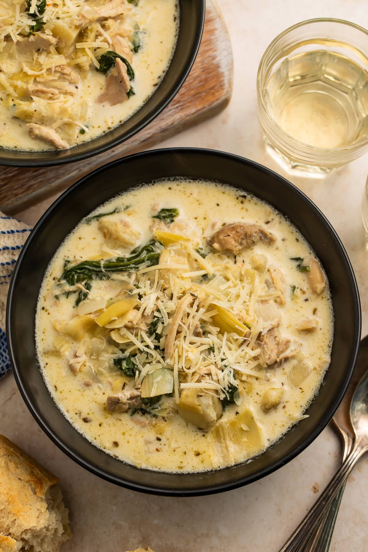Close up of a black bowl of creamy chicken, artichoke and spinach soup.