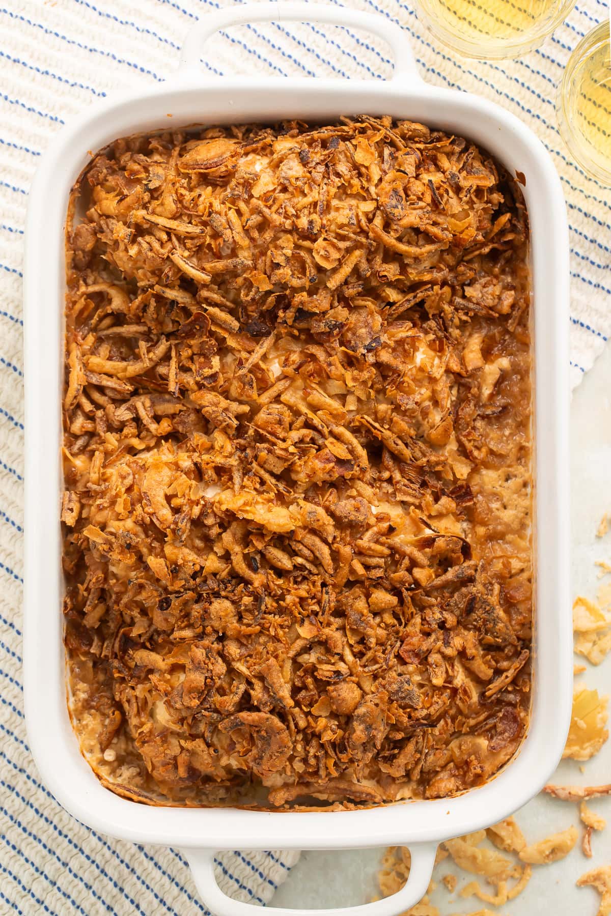 Overhead image of a French onion chicken bake topped with crispy onions in a white baking dish.