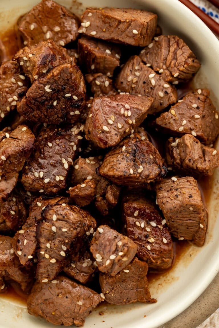 Close up of a bowl of hibachi steak bites scattered with sesame seeds.