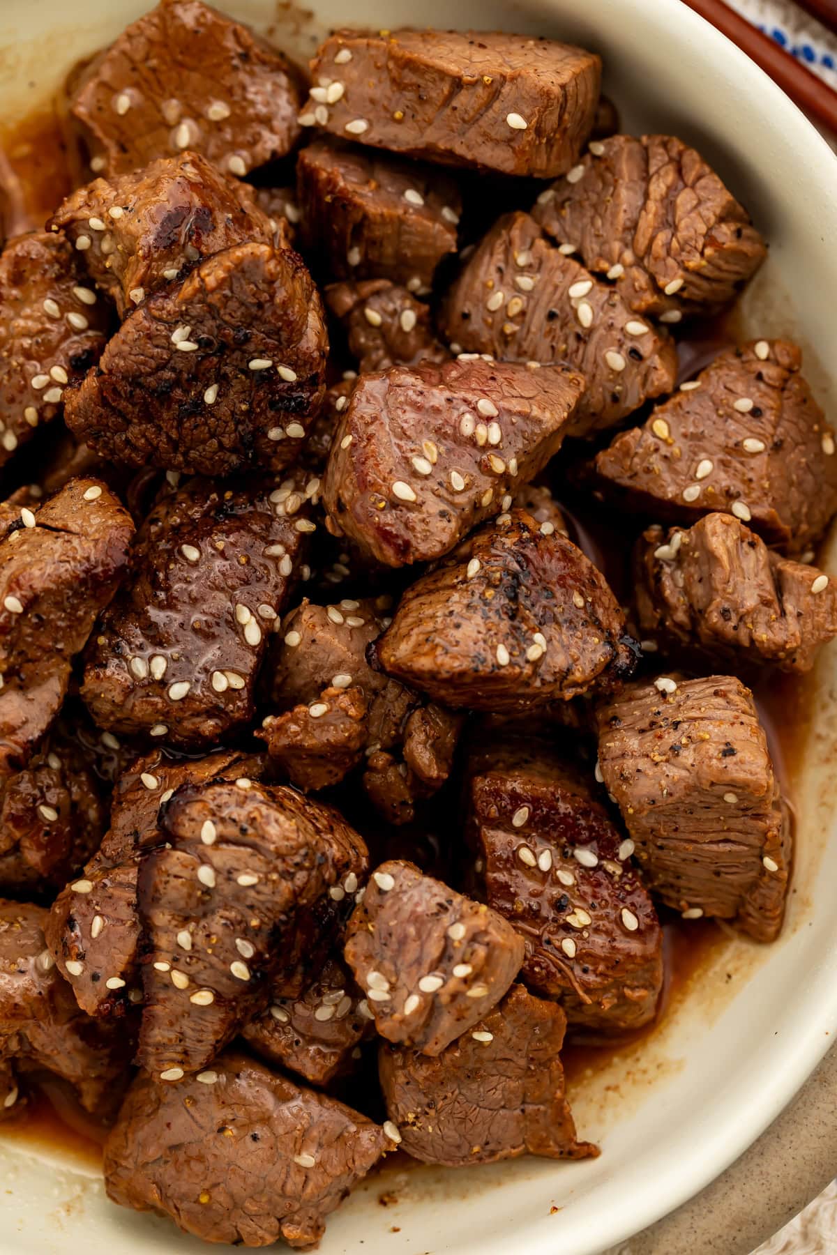 Close up of a bowl of hibachi steak bites scattered with sesame seeds.