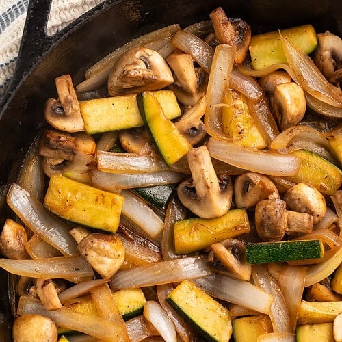 Close up of hibachi-style zucchini, onions and mushrooms in a cast iron skillet.