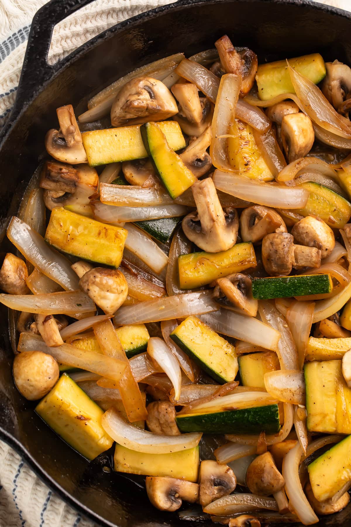Close up of hibachi-style zucchini, onions and mushrooms in a cast iron skillet.