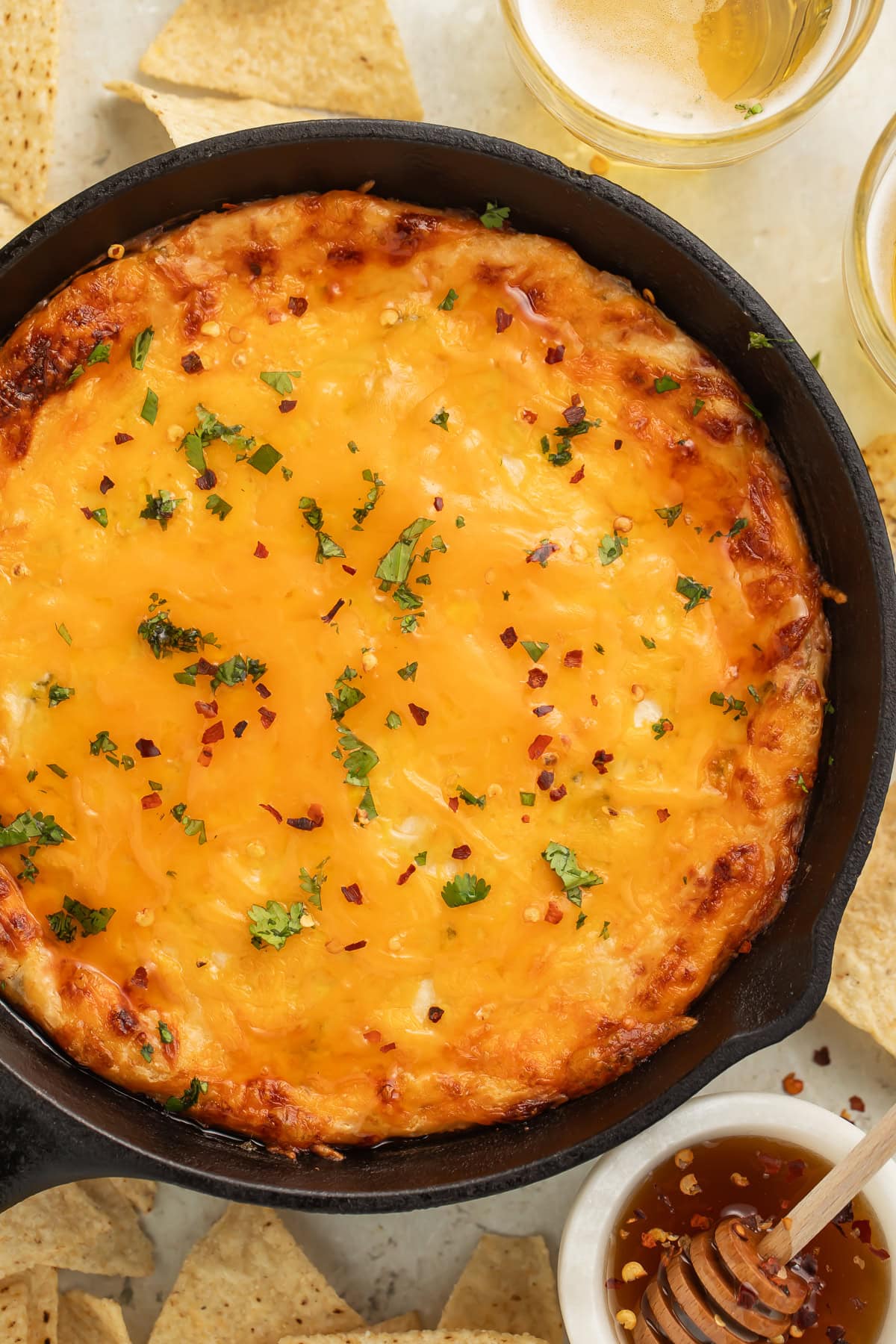 Overhead image of a baked hot honey and chicken dip in a cast iron skillet.