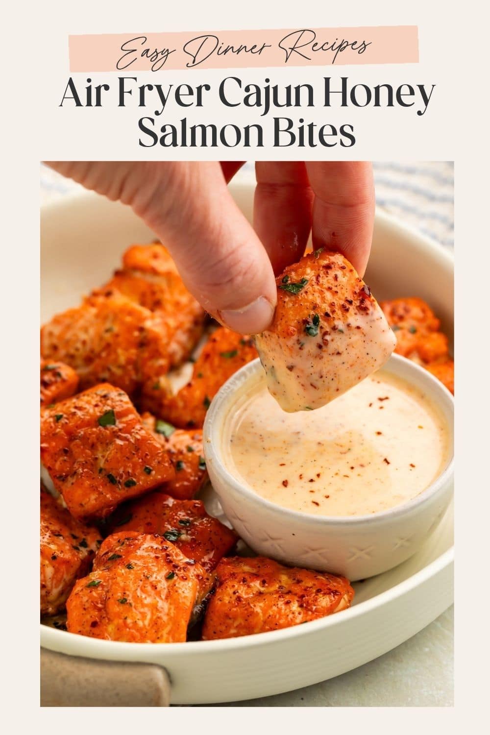 Salmon bite with a Cajun honey glaze being dipped into a creamy dipping sauce. There is a frame on the image with Pinterest-friendly text.