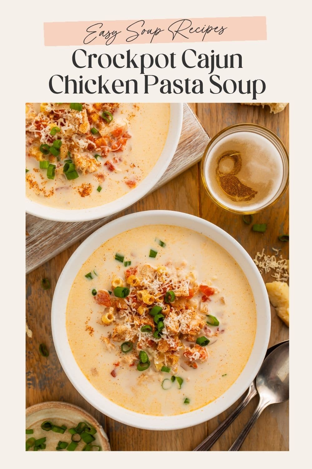 Overhead image of a bowl of creamy Cajun chicken and pasta soup topped with shredded cheese and green onions. There is a fram eon the image with Pinterest-optimized text.