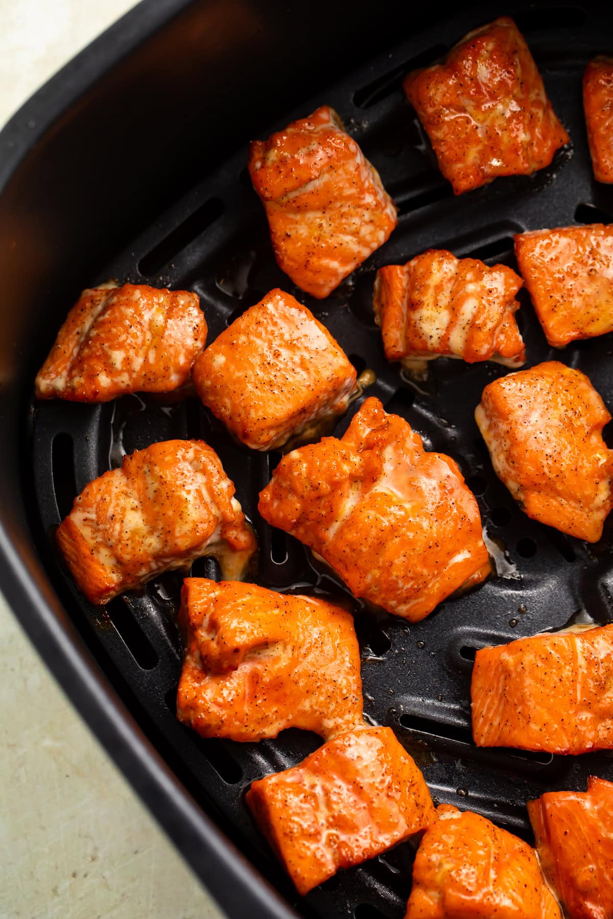 Close up of salmon bites in an air fryer basket.