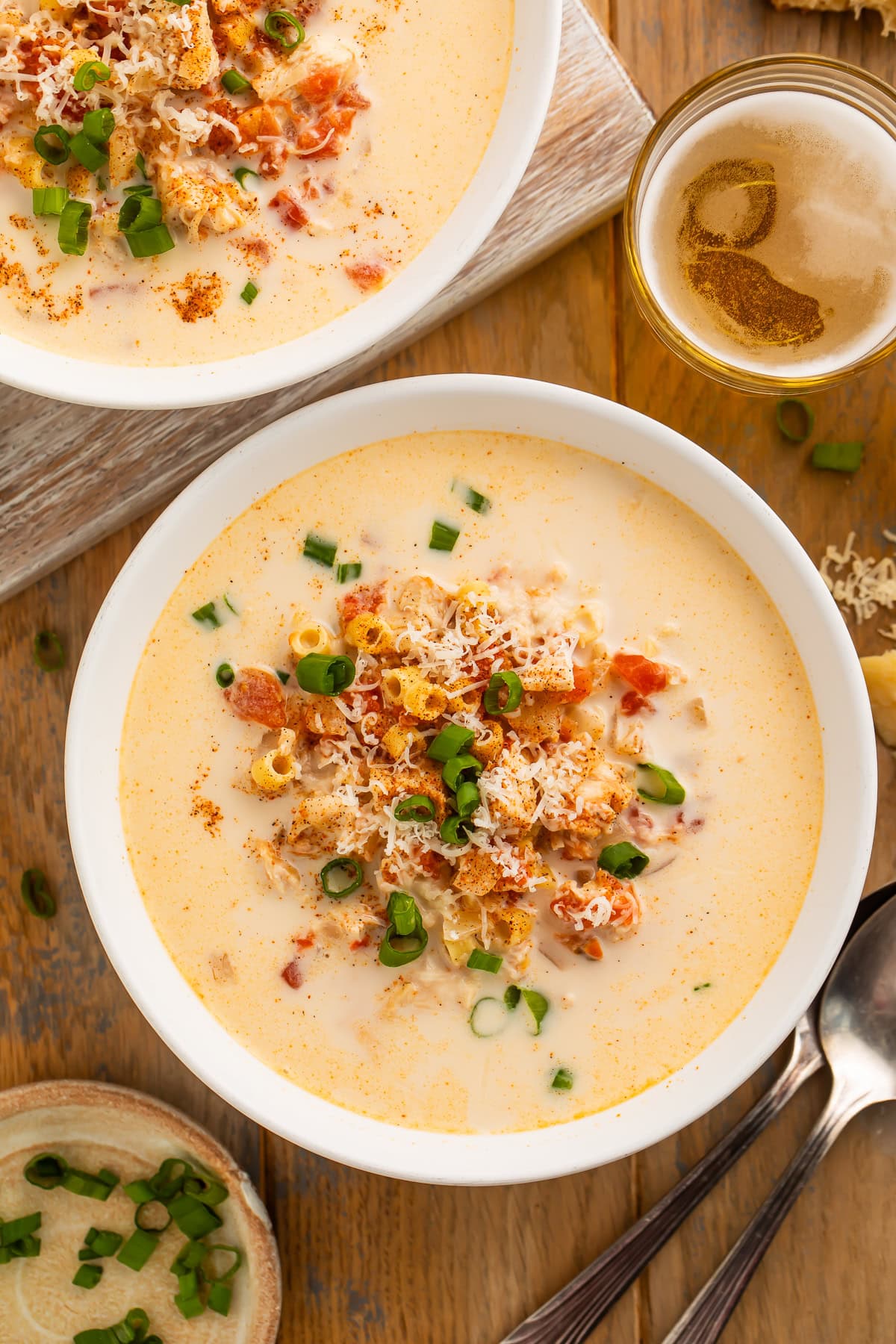 Overhead image of two bowls of creamy cajun chicken soup with chunks of tomato, garnished with green onion.