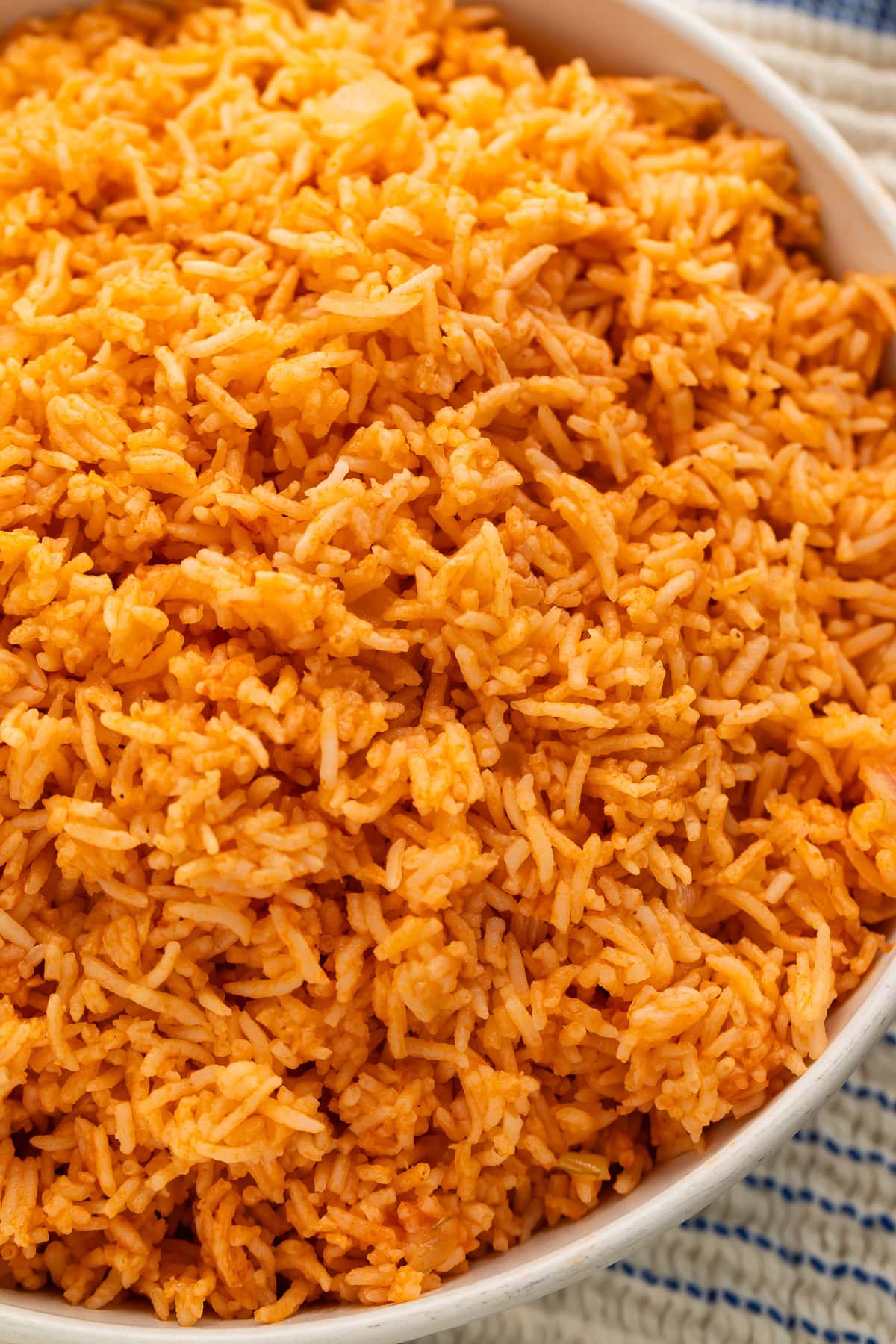 Close up of Spanish rice with tomato flavors in a white serving bowl.