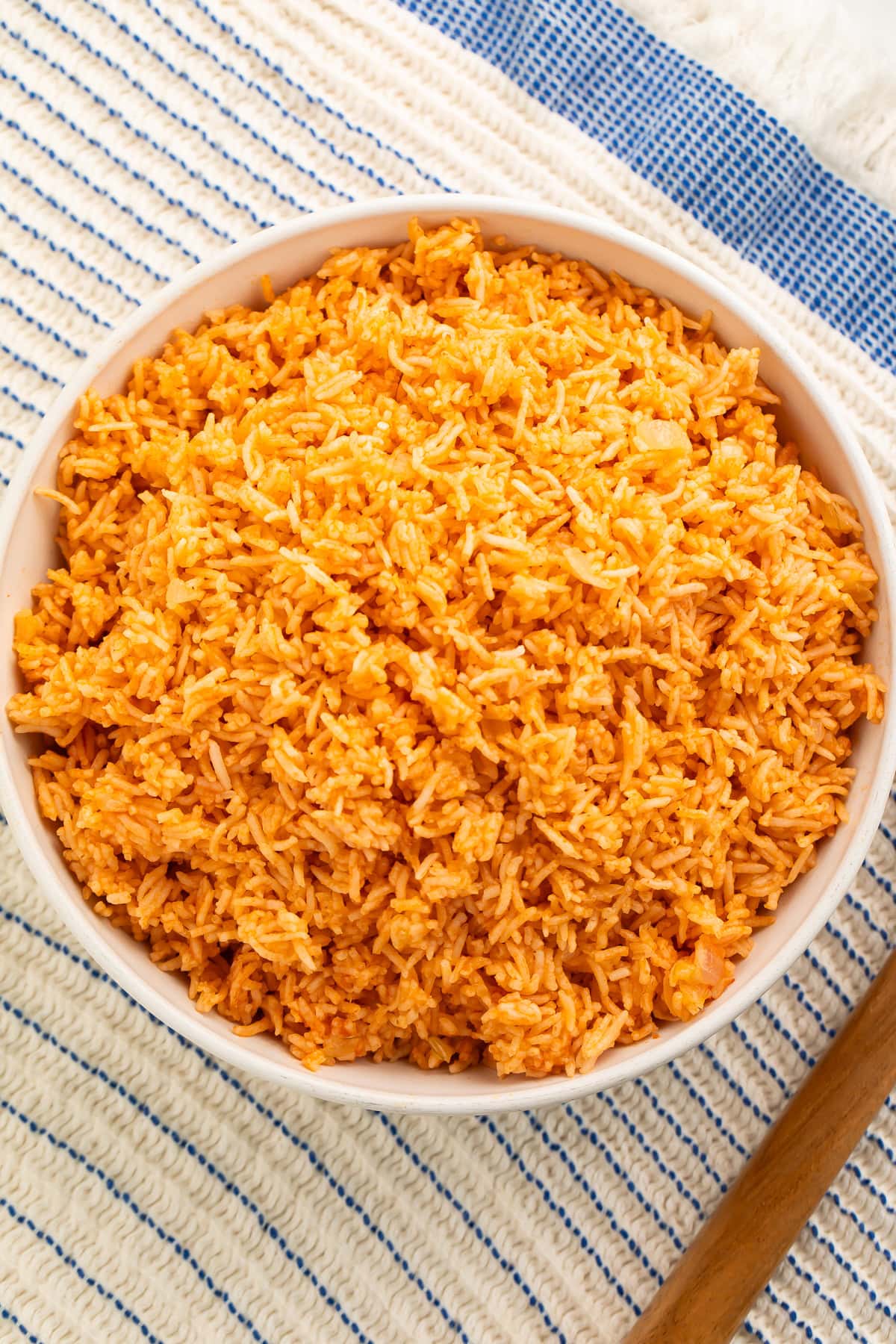 White bowl of Spanish rice on a blue and white kitchen towel.