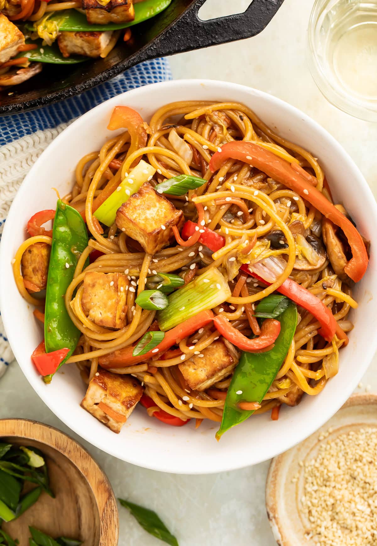 White bowl of tofu lo mein noodles with vegetables.