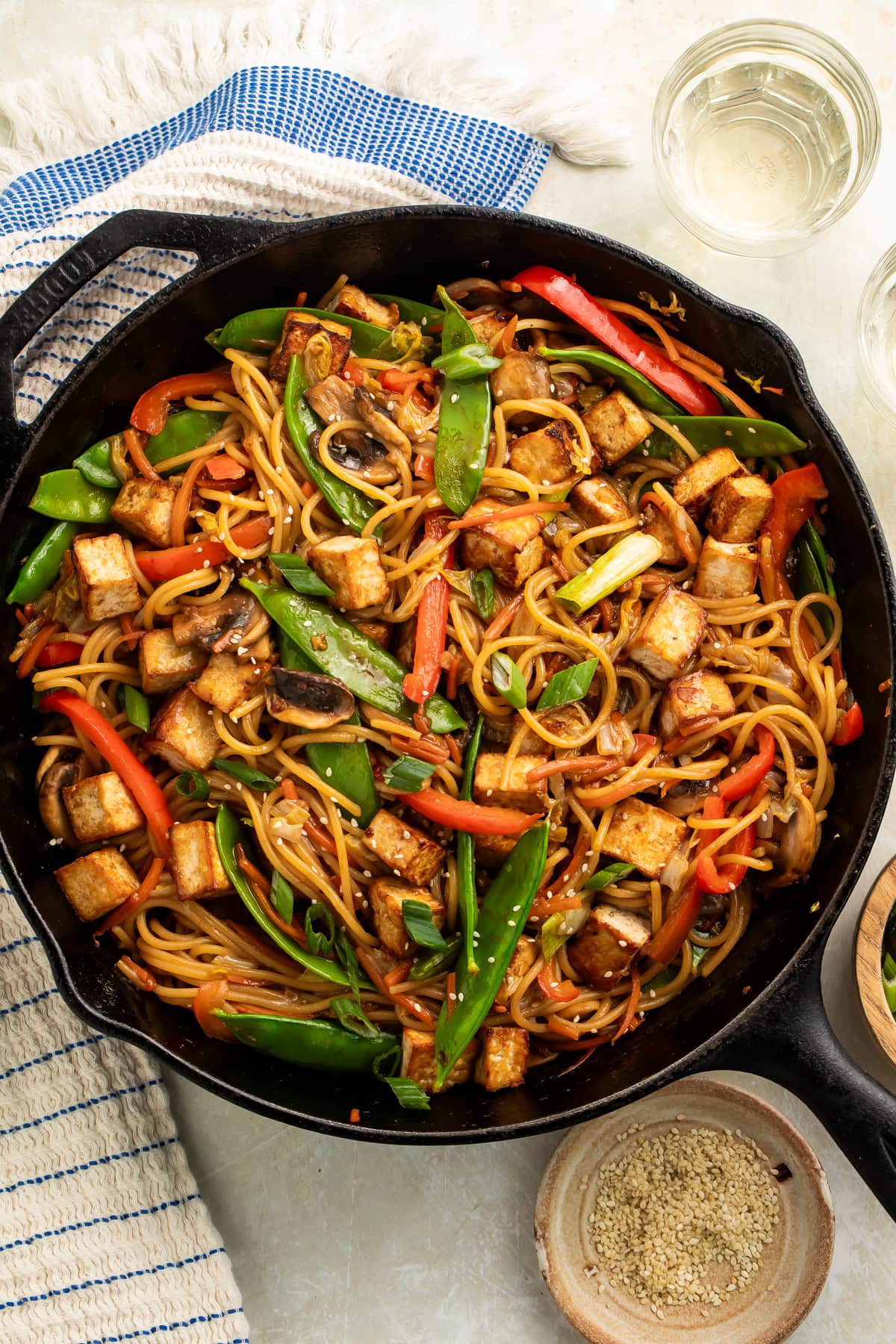 Cast iron skillet of le mein vegetable noodles with cubes of crispy tofu.