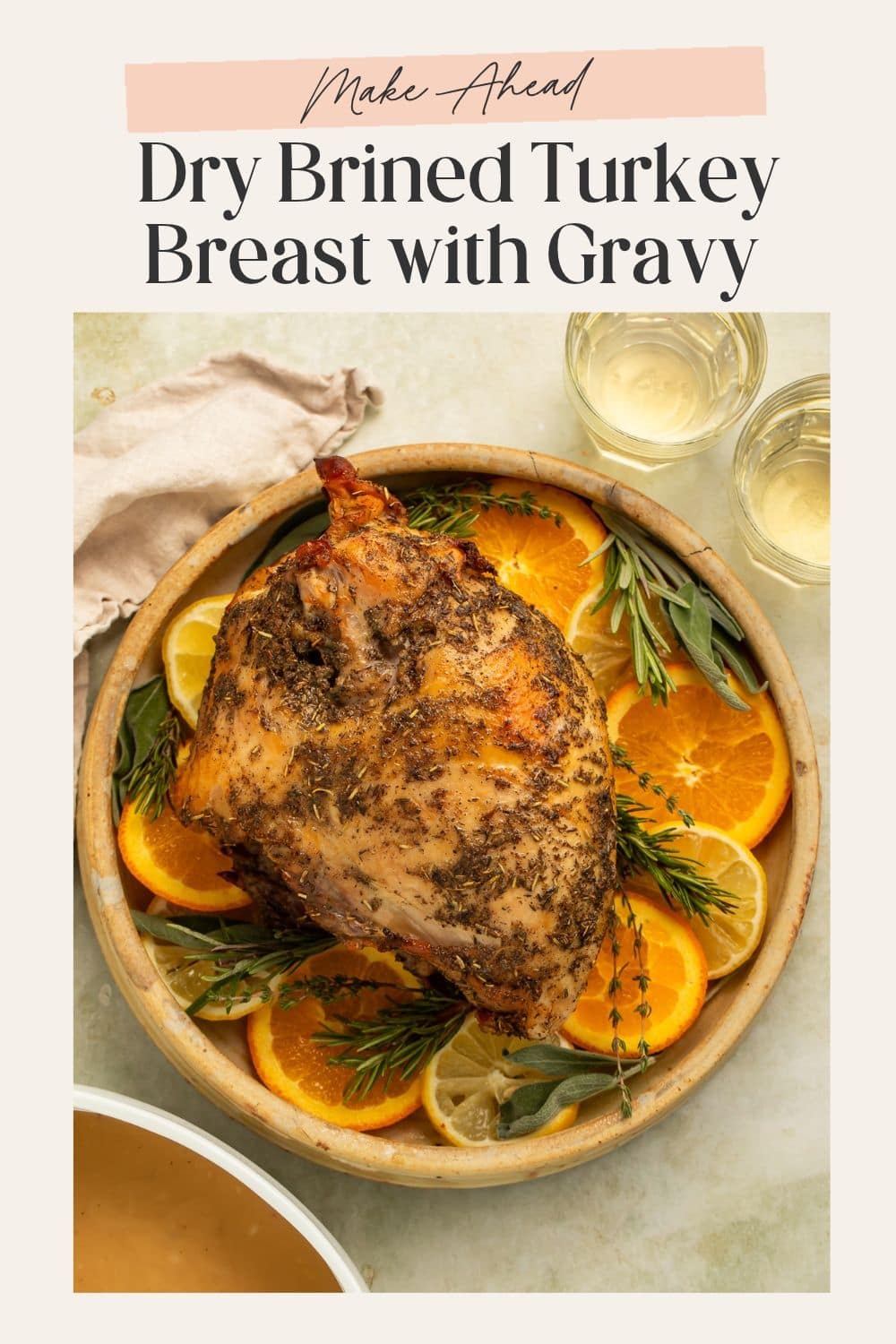 Whole dry brined turkey breast on a platter of sliced oranges and woody herbs. There is a frame on the image with Pinterest-friendly text.
