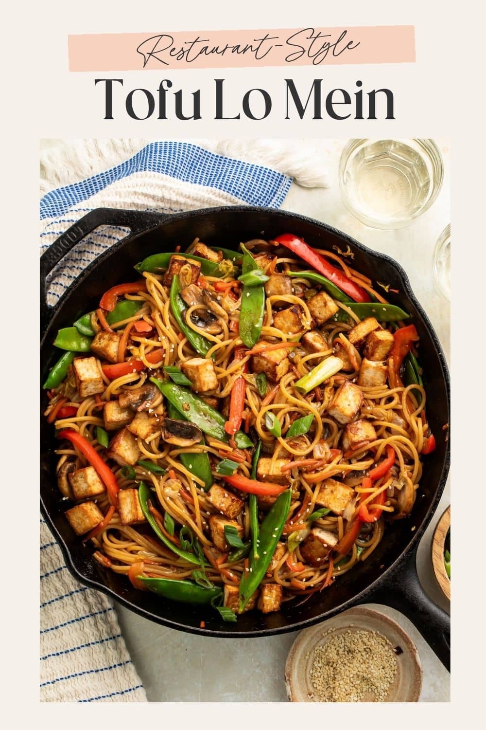 Cast iron skillet of tofu lo mein with peppers and snap peas. There is a frame on the image with Pinterest-friendly text.