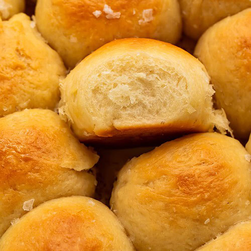 Close up of parker house rolls scattered with flaky sea salt.