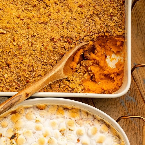 Two sweet potato casseroles pictured overhead with a spoonful missing to show the sweet potato layer. One is topped with streusel and the other mini marshmallows.