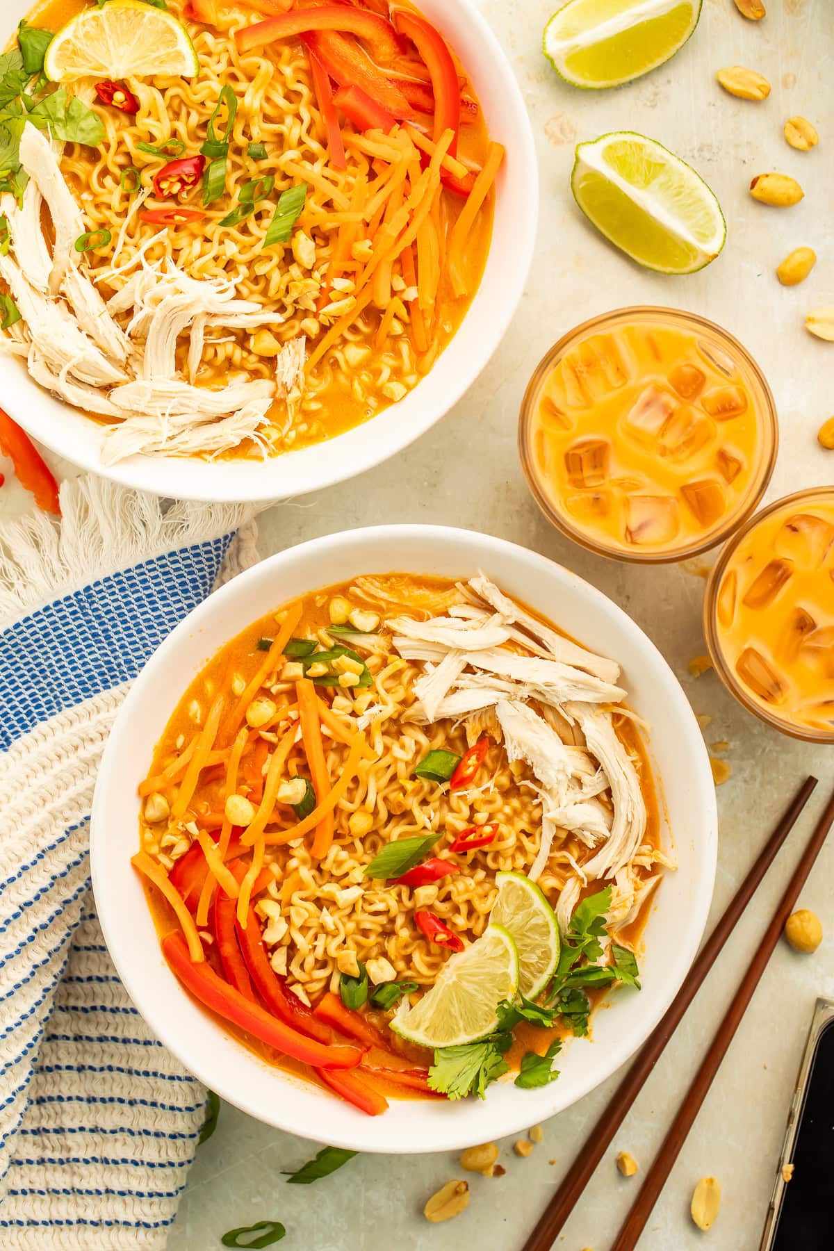 Overhead images of two bowls of Thai peanut butter and chicken ramen served alongside two glasses of creamy Thai iced tea.